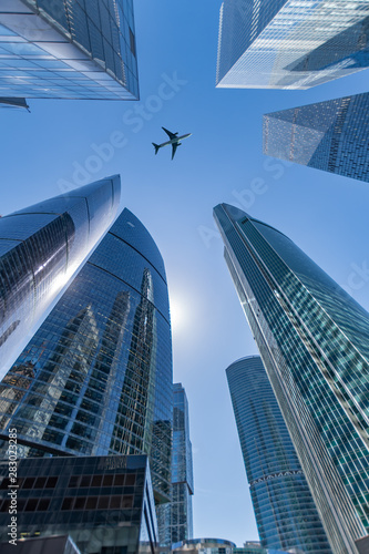 Business center  skyscrapers on sky background and flying plane.