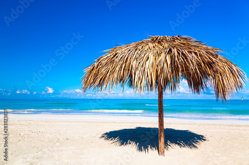 Straw umbrella on a beach. Vacation background. Idyllic beach landscape.