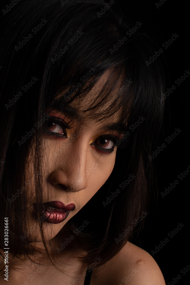 Southeast asian woman with dark tone makeup on black background, portrait photograph