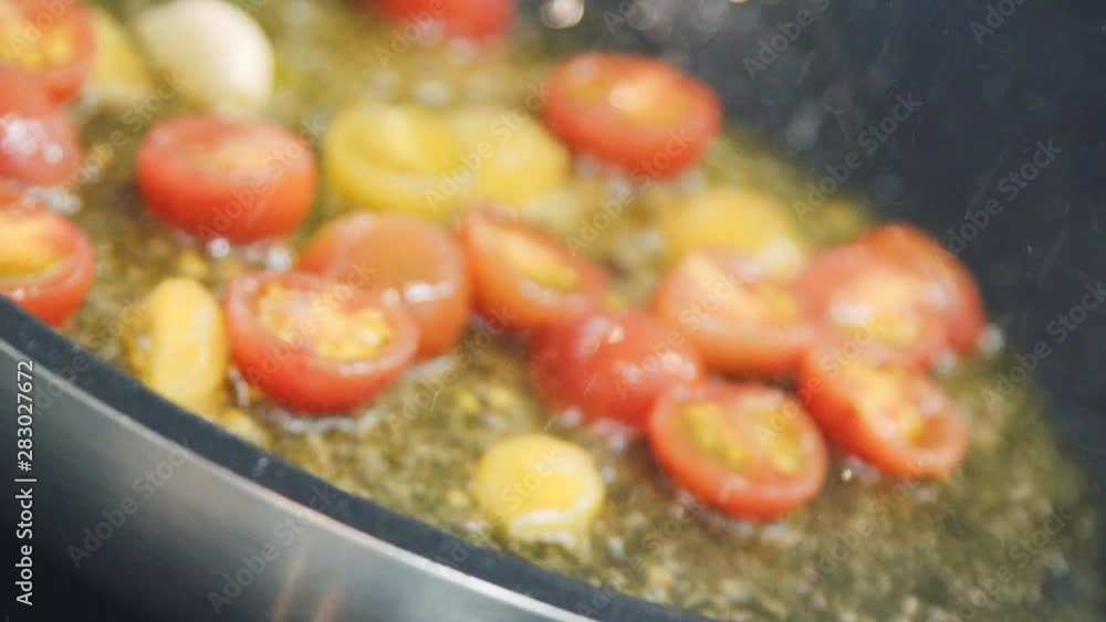 The tomatoes are frying on the frying pan. The chef is frying cherry tomatoes. Someone is making red and yellow tomatoes. Close up food video restaurant kitchen. The tomatoes are frying on the frying pan. The chef is frying cherry tomatoes. Someone is making red and yellow tomatoes. Close up food video restaurant kitchen.
