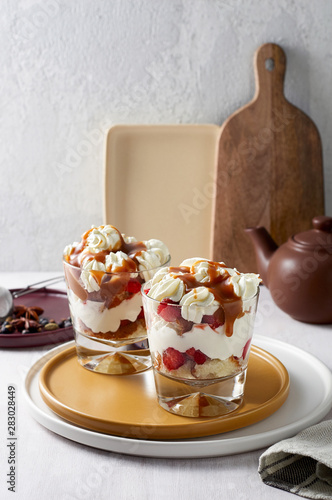 Layered dessert Trifle with vanilla cake, whipped cream, salted caramel and fresh strawberry