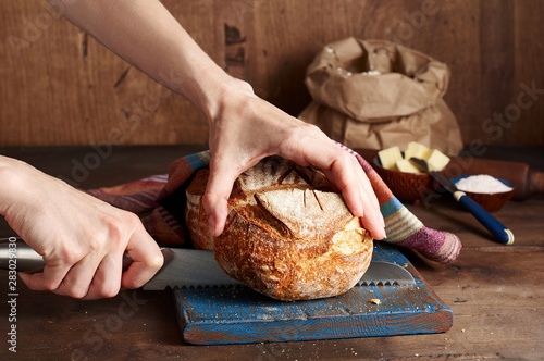 Hands cutting Artisan sourdough toast bread on blue wooden board. Simple breakfast