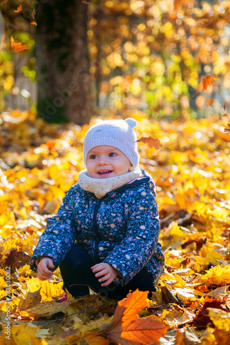 beautiful baby girl with yellow leaves on a background
