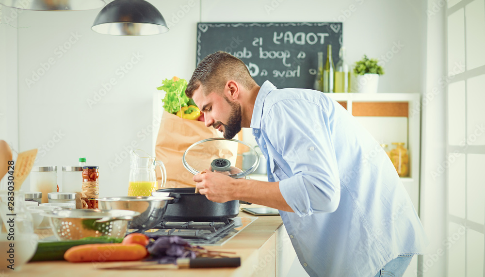 Smiling and confident chef standing in a large kitchen tasting Smiling and confident chef standing in a large kitchen tasting