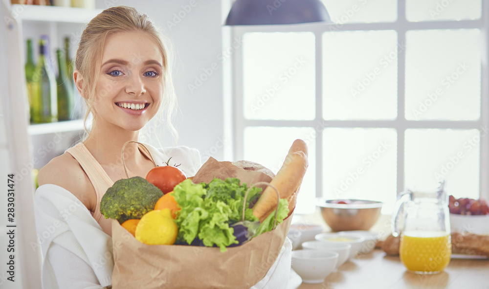 Young woman holding grocery shopping bag with vegetables Standi Young woman holding grocery shopping bag with vegetables Standi