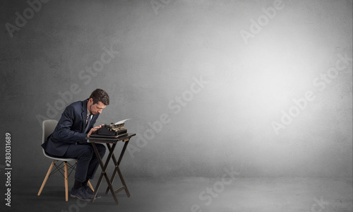 Man working hard on a typewriter in an empty space