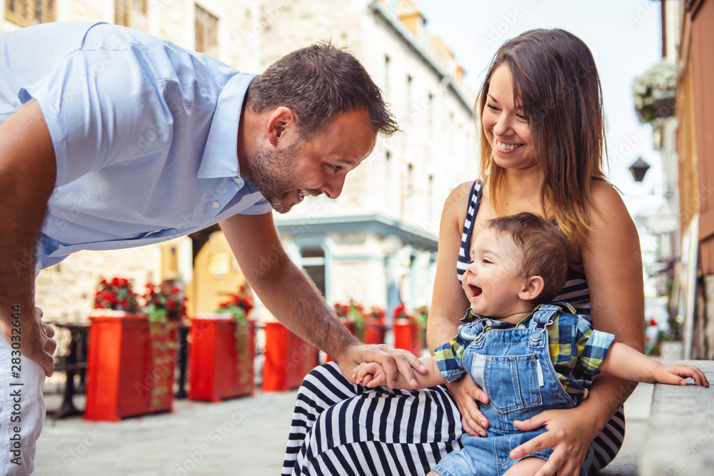 Obraz premium Happy family of three on the street with baby