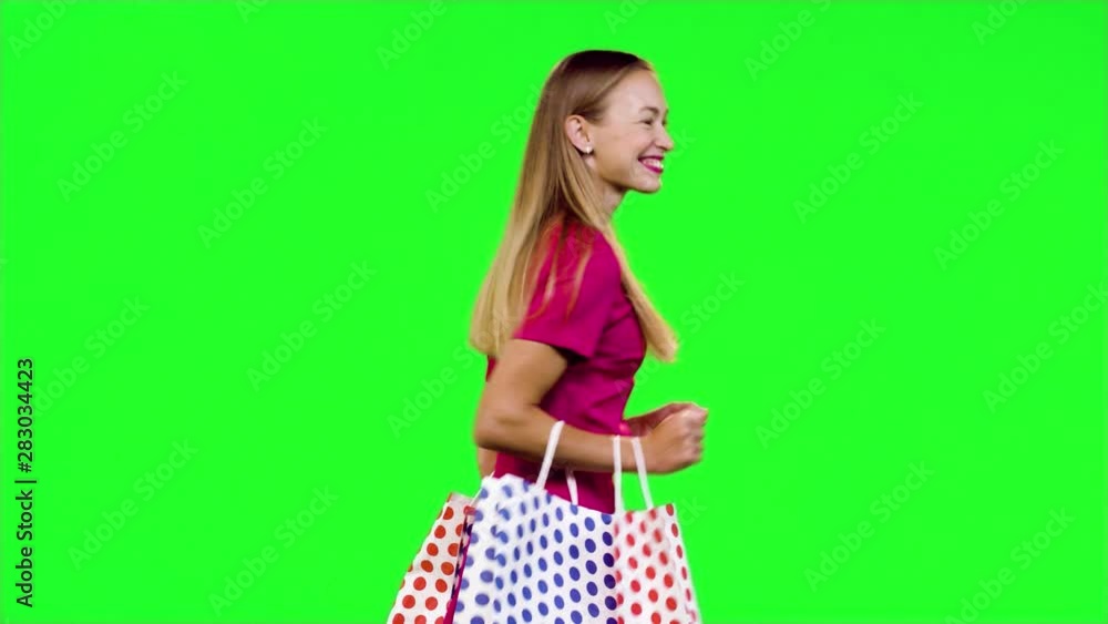 Stylish woman walks happy and smiles as she looks around in medium shot over green screen. Stylish woman walks happy and smiles as she looks around in medium shot over green screen.