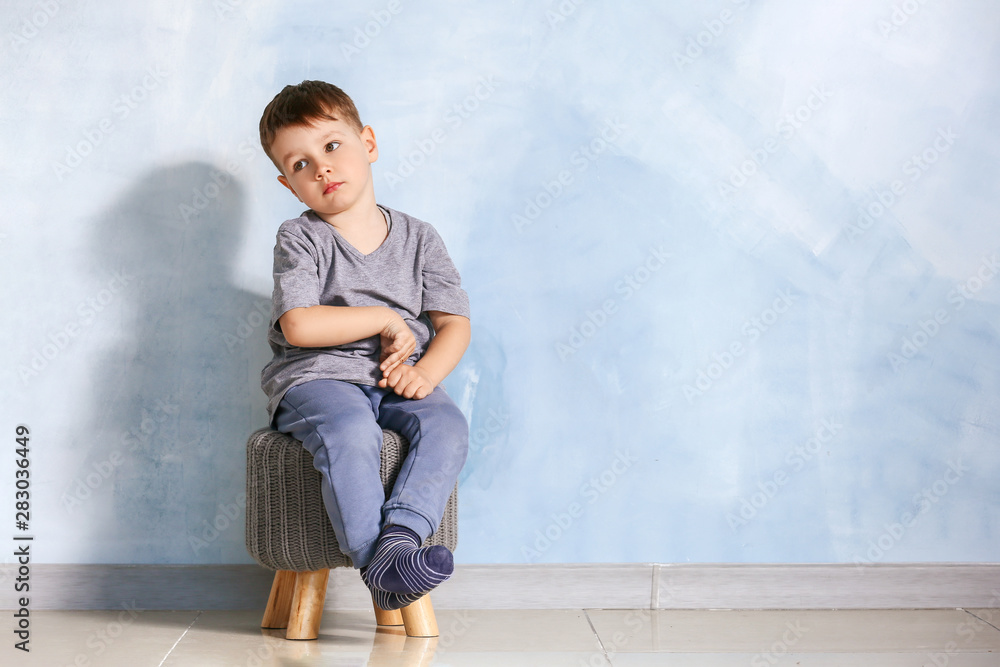 Little boy with autistic disorder sitting near light wall Little boy with autistic disorder sitting near light wall