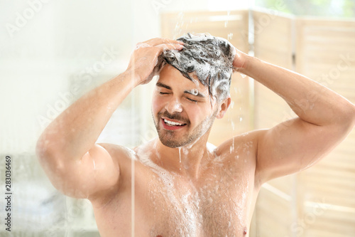 Handsome man washing hair a...