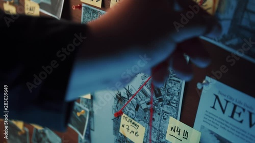 Detective board with photos of suspected criminals, crime scenes and evidence with red threads