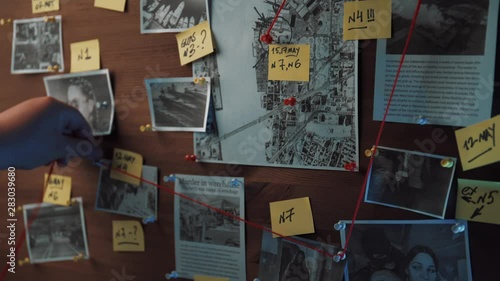 Detective board with photos of suspected criminals, crime scenes and evidence with red threads