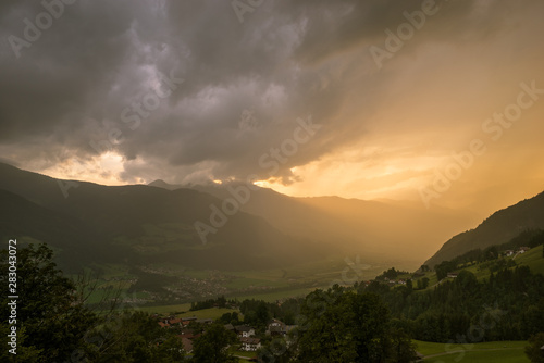 Dramatic sky over the mountains at sunset. Sun rays shine in the valley.