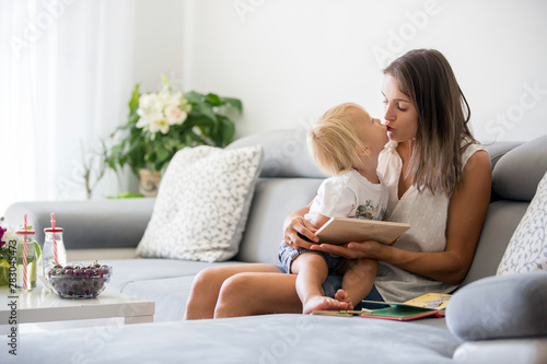 Charming mother, making puzzle with her cute toddler baby boy at home