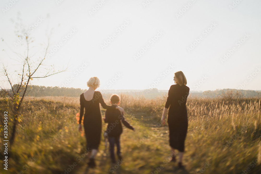 Samesex caucasian lesbian family with a child and a dog walking outdoors on the background of beautiful nature. Mothers having fun with their son. Samesex caucasian lesbian family with a child and a dog walking outdoors on the background of beautiful nature. Mothers having fun with their son.