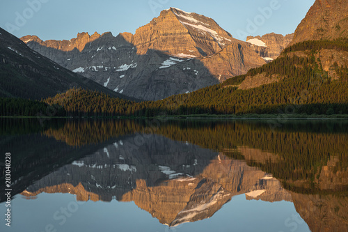 Mountains reflect in the morning light on Swiftcurrent Lake, Glacier National Park, Montana