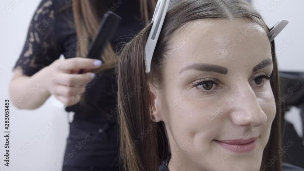 hairdresser makes hair lamination in a beauty salon for a girl with brunette hair hairdresser makes hair lamination in a beauty salon for a girl with brunette hair