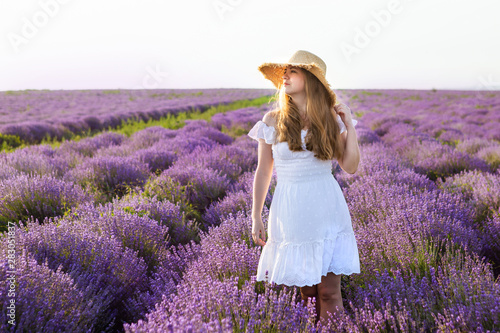 Woman in white dress, straw hat in lavender field.