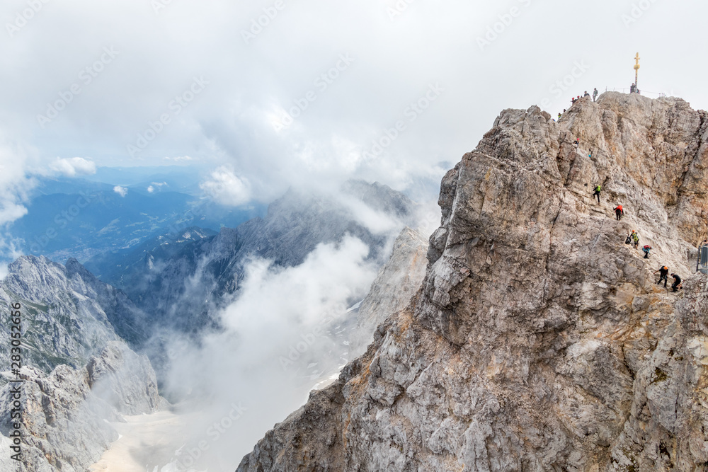 Gipfelkreuz Zugspitze mit Bergsteigern in Reihe, Bayern, Deutschland