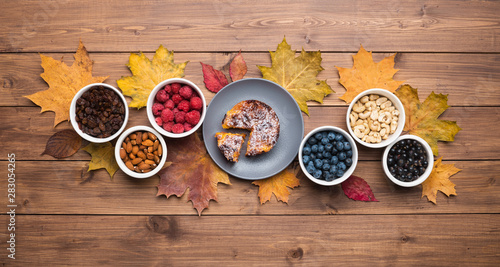 Seasonal autumn background. Frame of maple leaves and a cake over wooden background.