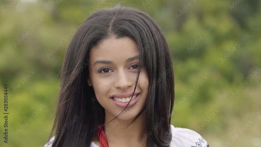 Portrait beautiful confident carefree African American girl looking at camera. Leisure and weekend of a pretty independent smiling young woman enjoying outdoors. Real people series. Slow motion. Portrait beautiful confident carefree African American girl looking at camera. Leisure and weekend of a pretty independent smiling young woman enjoying outdoors. Real people series. Slow motion.
