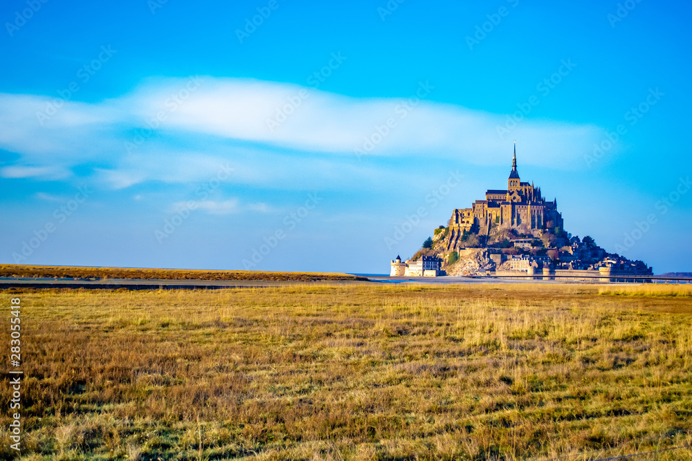 Stunningly beautiful medieval castle of Mont Saint Michel. Abbey, located on the island, enclosed by fortifications. It is washed by the sea from all sides. Beautiful blue sky and fluffy white clouds Stunningly beautiful medieval castle of Mont Saint Michel. Abbey, located on the island, enclosed by fortifications. It is washed by the sea from all sides. Beautiful blue sky and fluffy white clouds