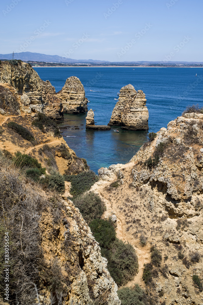 Vacation in Algarve - View of colourful cliffs off Ponta da Piedade headland and cliffs rising from the turquoise waters of the sea. Shore in distance