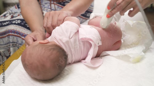 A close-up of a neonatologist performing ultrasound studying of infants hip joints. Hip dysplasia. Pediatric concept photo