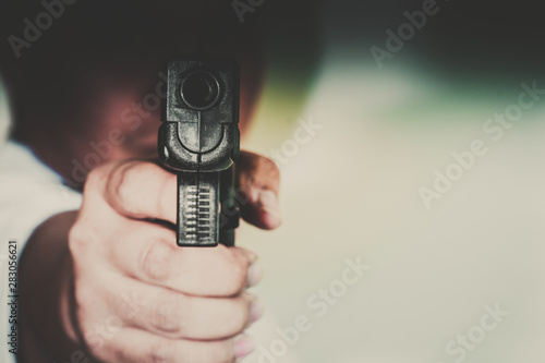 Man shooting gun, man pointing gun to camera, close-up image