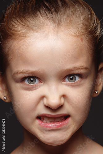 Close up portrait of little and emotional caucasian girl. Highly detail photoshot of female model with well-kept skin and bright facial expression. Concept of human emotions. Angry, looking at camera.