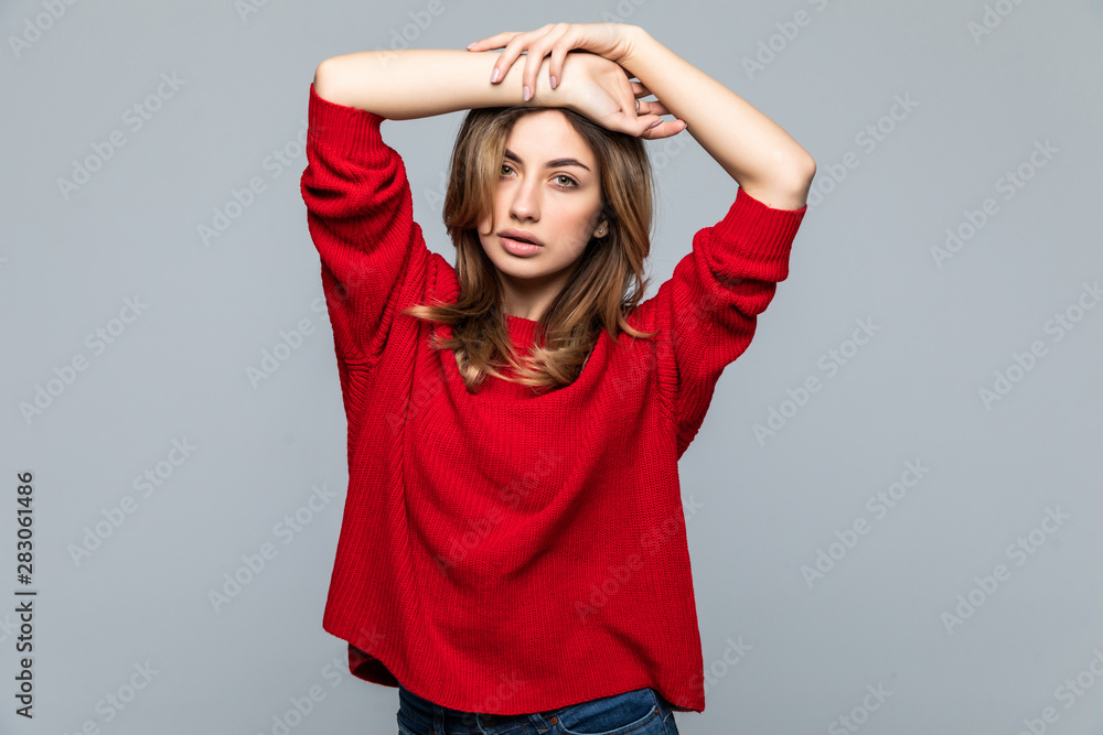 Smiling young woman in red sweater looking away over gray background Smiling young woman in red sweater looking away over gray background