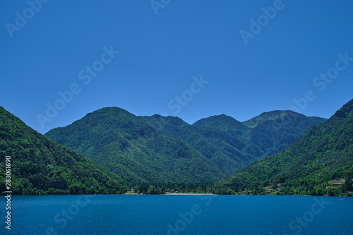 Panoramic view of Lake Ledro in the north of Italy In the Alps. Blue lake, in the background green mountains, blue sky.
