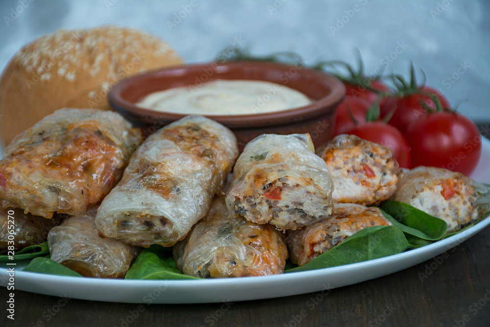 Spring roll with meat and vegetables served on a white dish with sauce. Dark wooden background. Spring roll with meat and vegetables served on a white dish with sauce. Dark wooden background.
