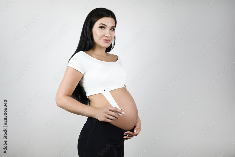 pregnant brunette beautiful woman holding lotion standing half a turn on isolated white background pregnant brunette beautiful woman holding lotion standing half a turn on isolated white background