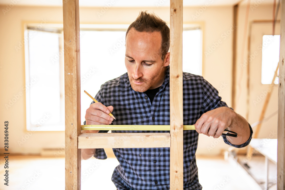 A man worker in the carpenter workroom renovation using tape