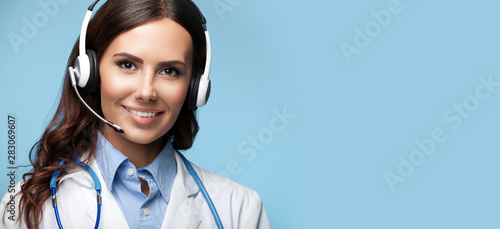 happy smiling young doctor in headset, against blue color, with copy space