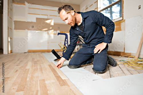 фотографія A Male Worker install wood floor on a house