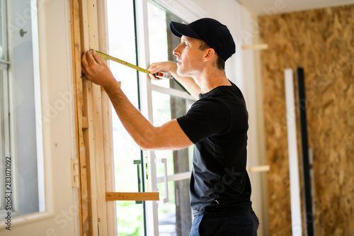 A handsome young man installing Double Sliding Patio Door in a new house construction site photo