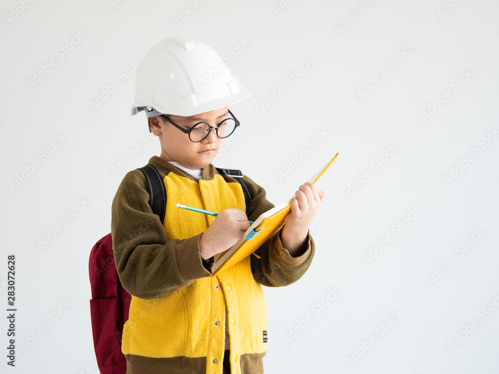 Asian boy with white engineer hat and whiting on the book education concept Asian boy with white engineer hat and whiting on the book education concept
