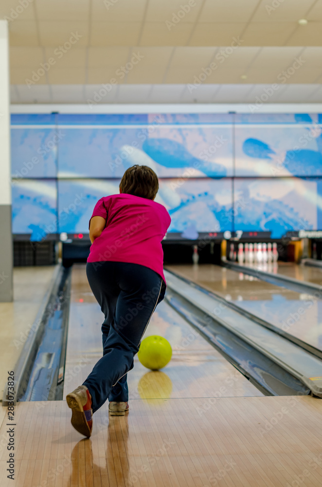 Young man throwing yellow ball in bowling game