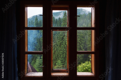 Through the wooden window of the room is visible mountain forest.
