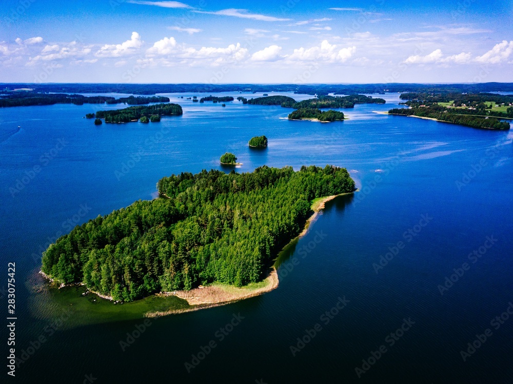 Aerial landscape view over blue lakes with islands and green forests in Finland.