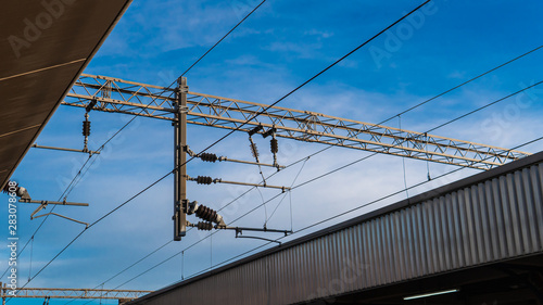 Overhead electric live wire for the train system in the UK against the blue sky.