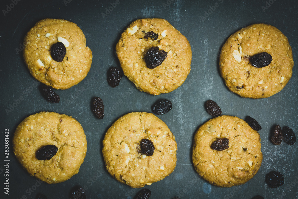 Fresh Oatmeal raisin cookies on black background, dark food concept.