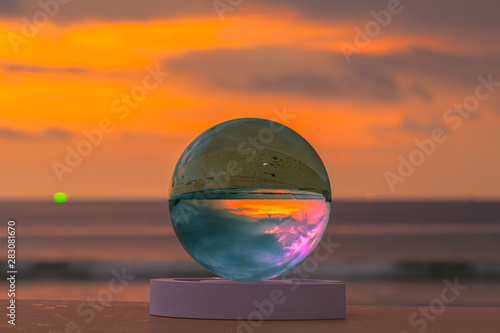 crystal glass ball sphere reveals sunrise seascape with spherical perspective on the beach in Phuket island