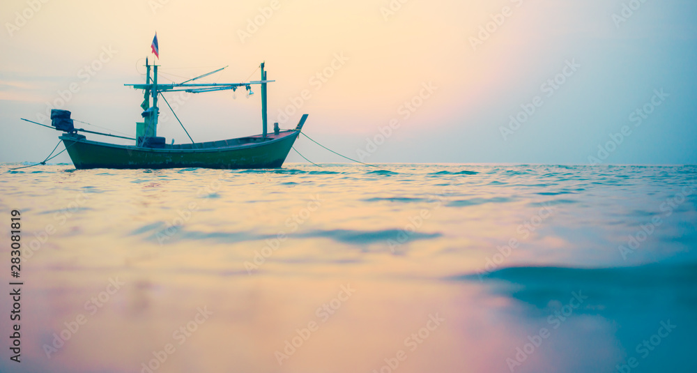 Fisherman's boat floats in the sea In the morning the sun is shining and the calm sea waves.