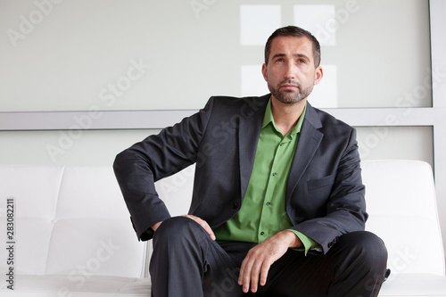Photography handsome businessman in suit and green shirt sitting indoors and looking pensive