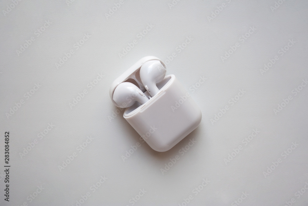 Wireless ear buds in glossy white plastic case isolated on white background Wireless ear buds in glossy white plastic case isolated on white background