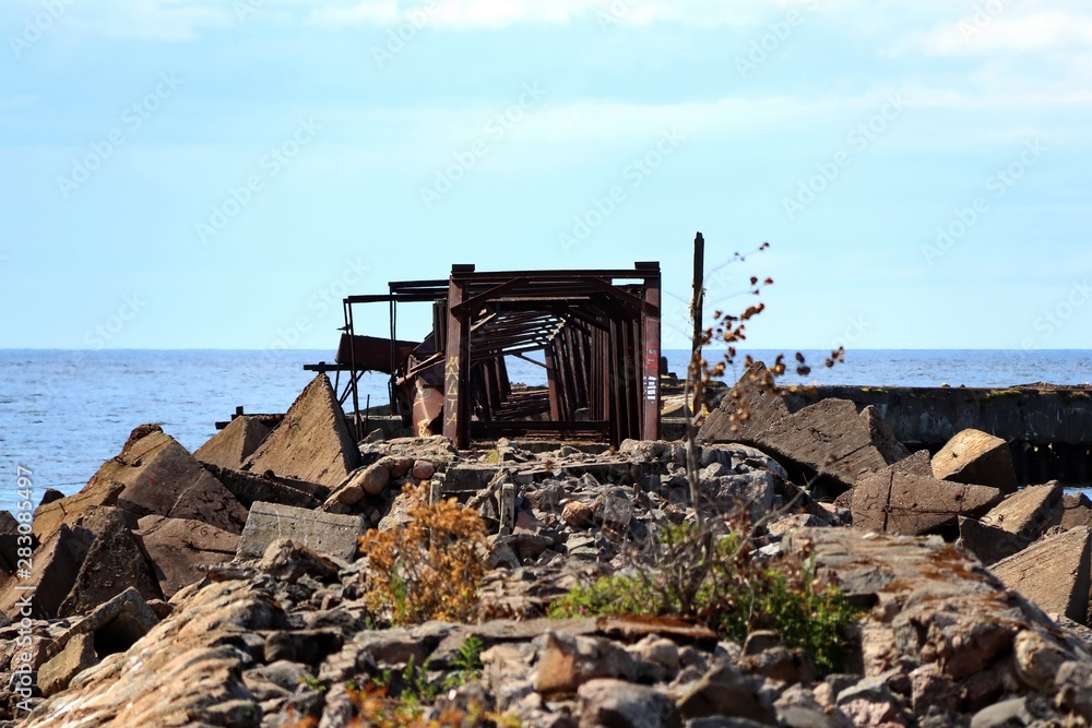 old abandoned pier on the beach with rusty metal structure old abandoned pier on the beach with rusty metal structure