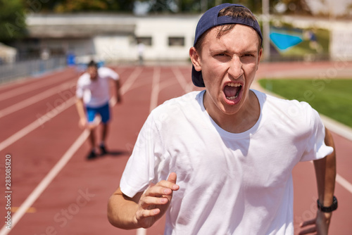 Young athlete man racing on running track with the opponent
